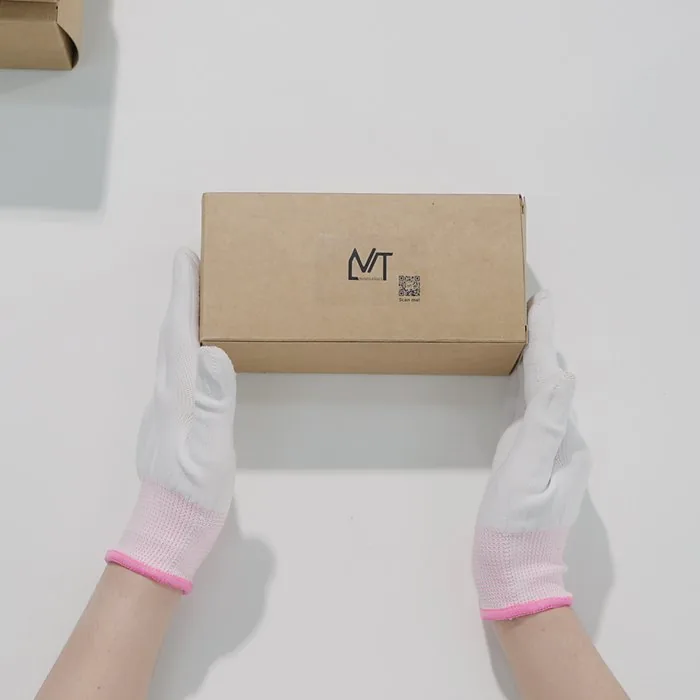 Gloved hands packing a finished frame into an MT-branded kraft box